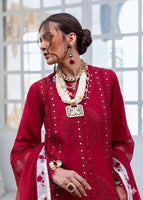 Woman wearing a red embroidered outfit with jewelry in a bright indoor setting